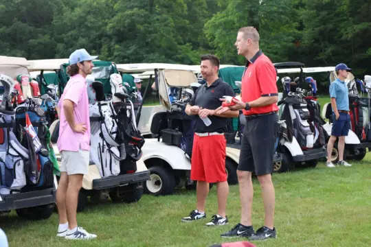 Golfers talk by the carts before the tournament