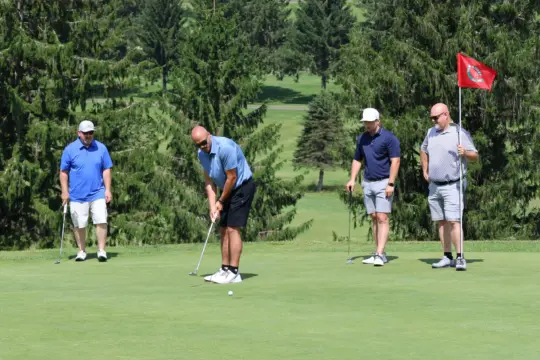 Golfer watches ball roll toward the hole.