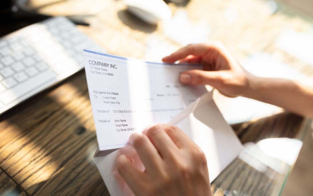 A person opens an envelope with a work paycheck inside.