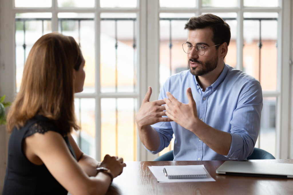 A young adult manager describes a project to their employee.