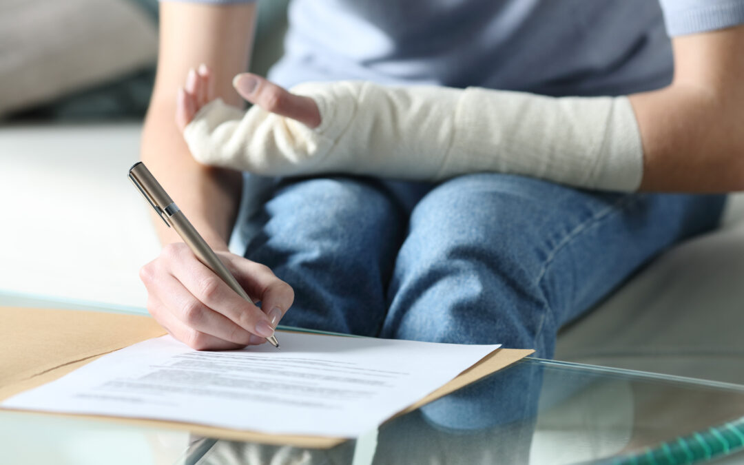 A person with an injured arm fills out disability insurance forms.