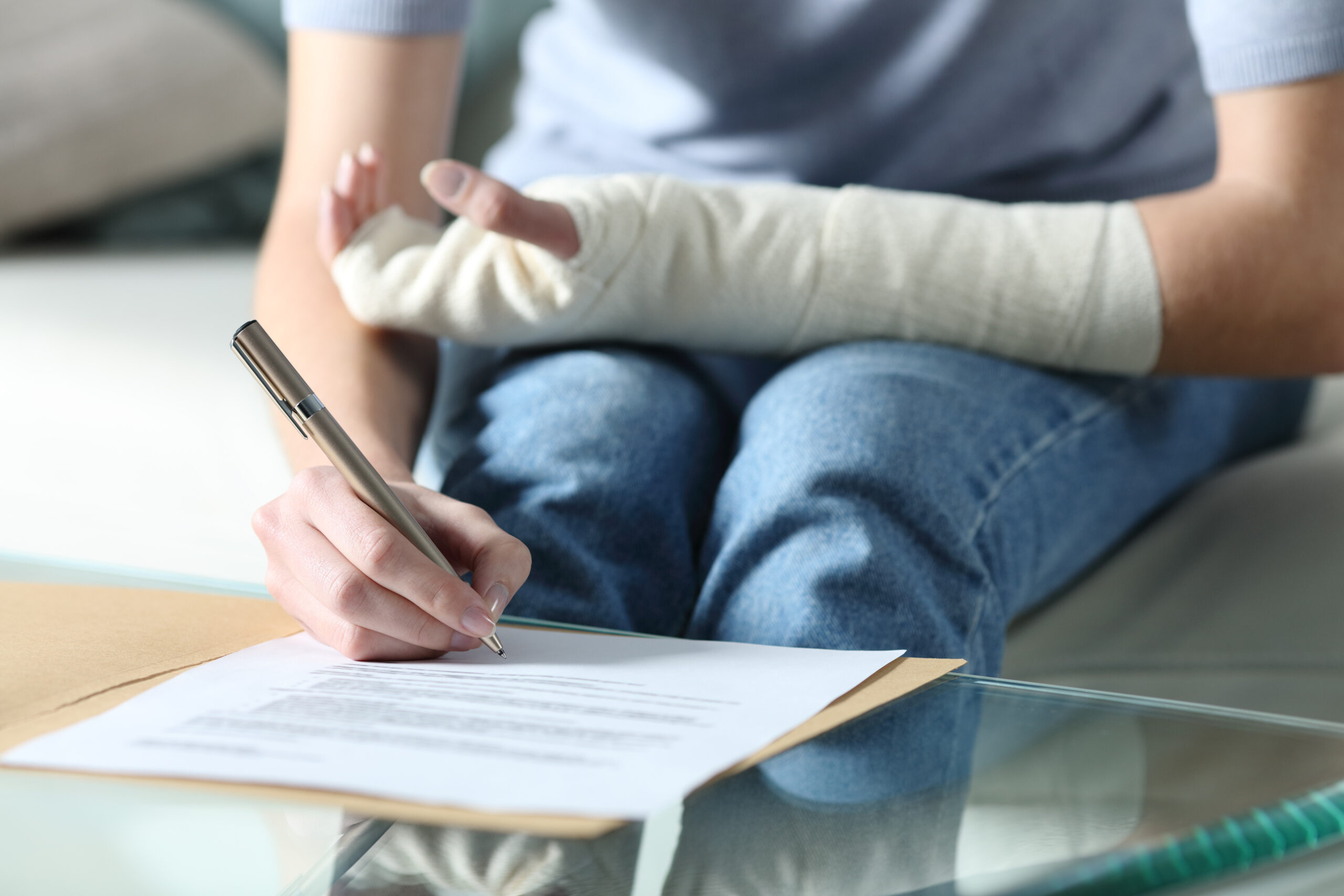 A person with an injured arm fills out disability insurance forms.