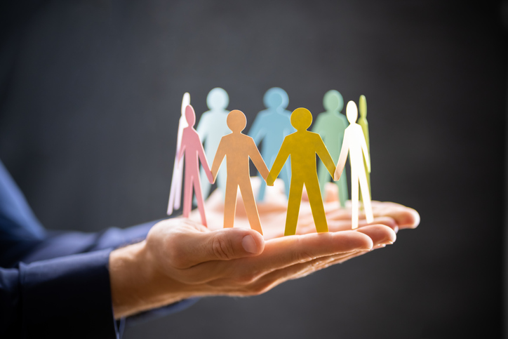 Close-up of a hand holding colorful paper cutout figures in a circle, symbolizing teamwork, unity, and employee retention.