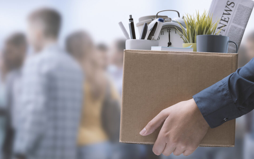 An unemployed office worker carrying personal belongings in a box.