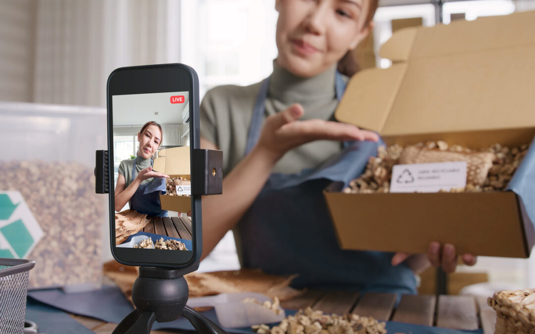 A young small business owner shows off her product to the camera as she makes a video.