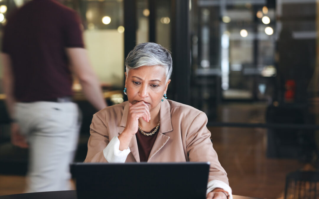 A corporate businesswoman looks at her laptop with concern.