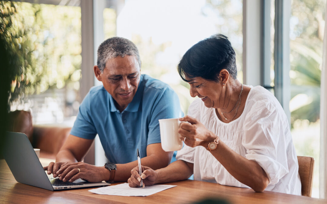 A senior couple works on their financial plan in front of a laptop.