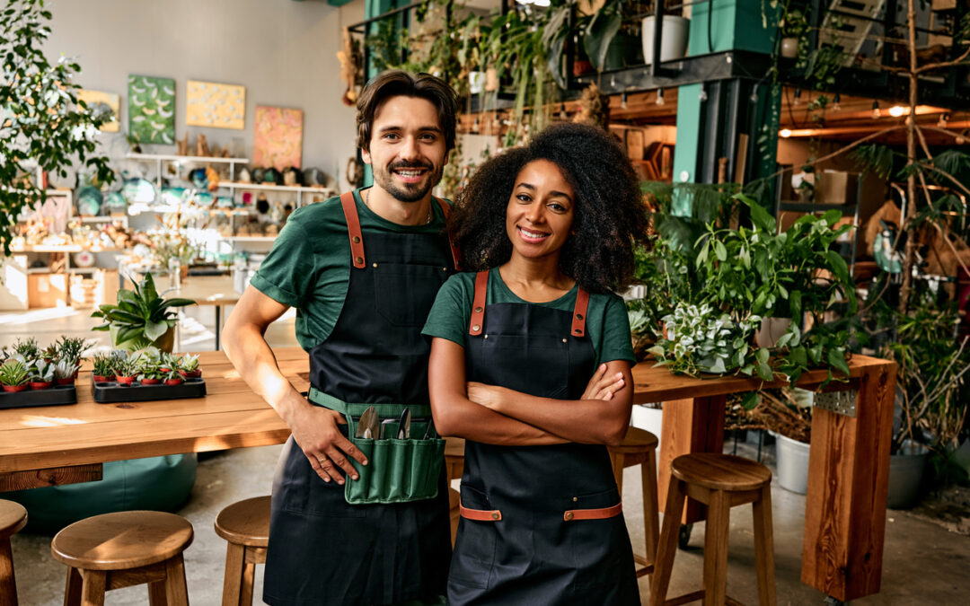 A young couple smile in front of the plants in their shop.