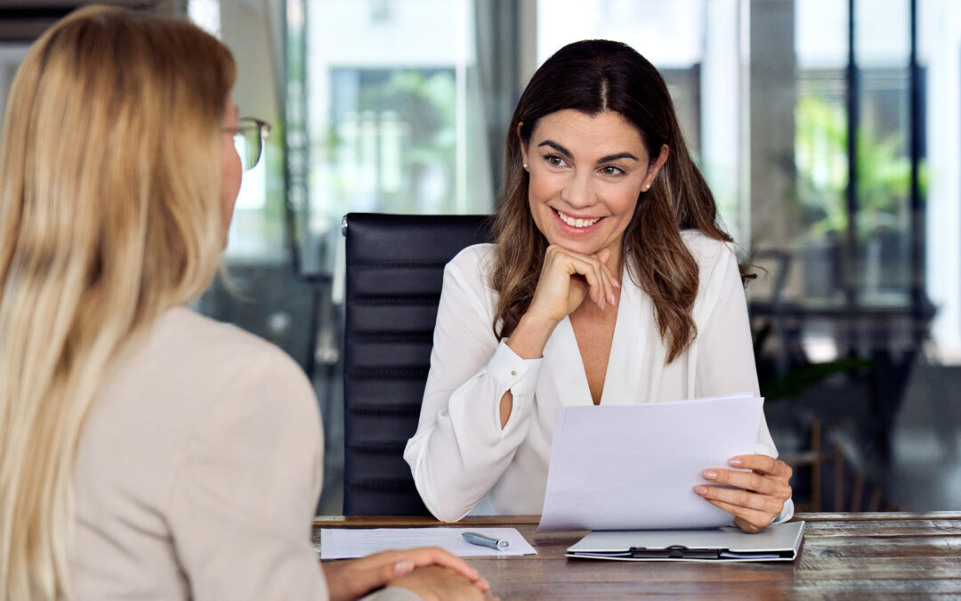 A hiring manager happily interviews a new employee.