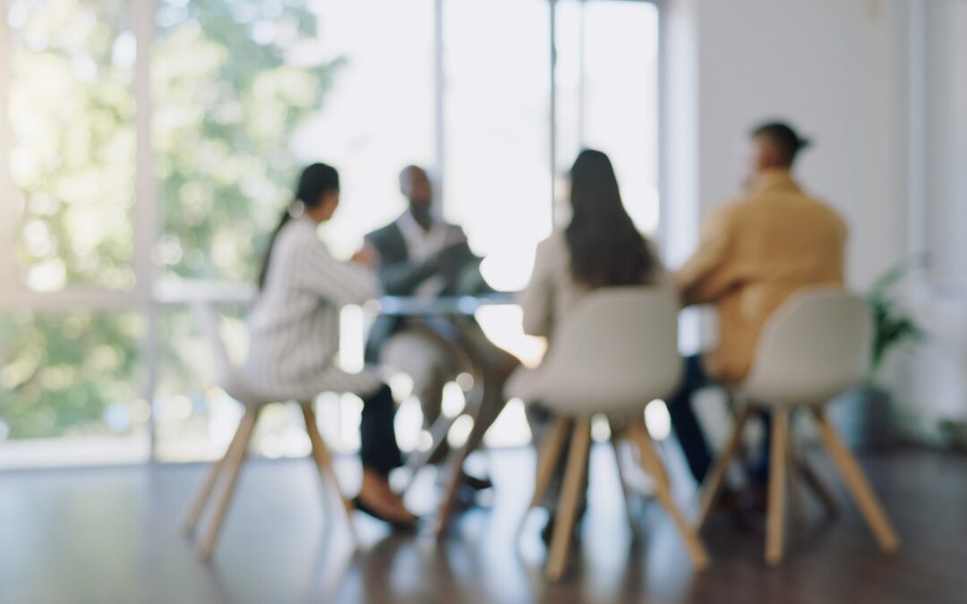 A blurred image of a group of business co-workers in a meeting.