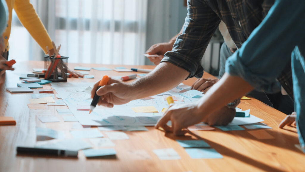 A team of workers using markers and pens on sticky notes.