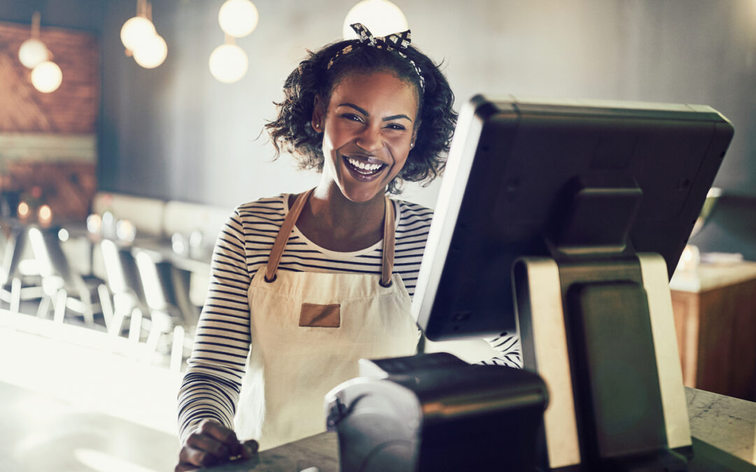 Young business owner smiles as she inputs customer orders.