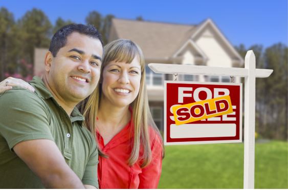 Couple in front of a sold house sign